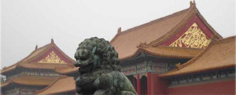 A Chinese statue of a lion at an ancient building.