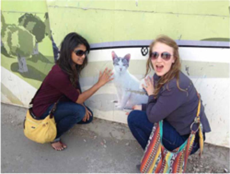 Brianna Baar with friend in front of a cat mural in the Middle East.