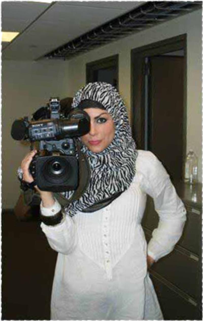 Imaan Ali poses for a photo with a television camera.