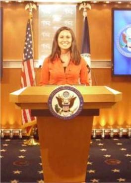 Student in front of a podium with a US government seal on it.