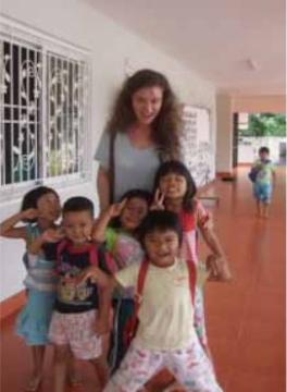 Student takes picture with children during a volunteer trip.