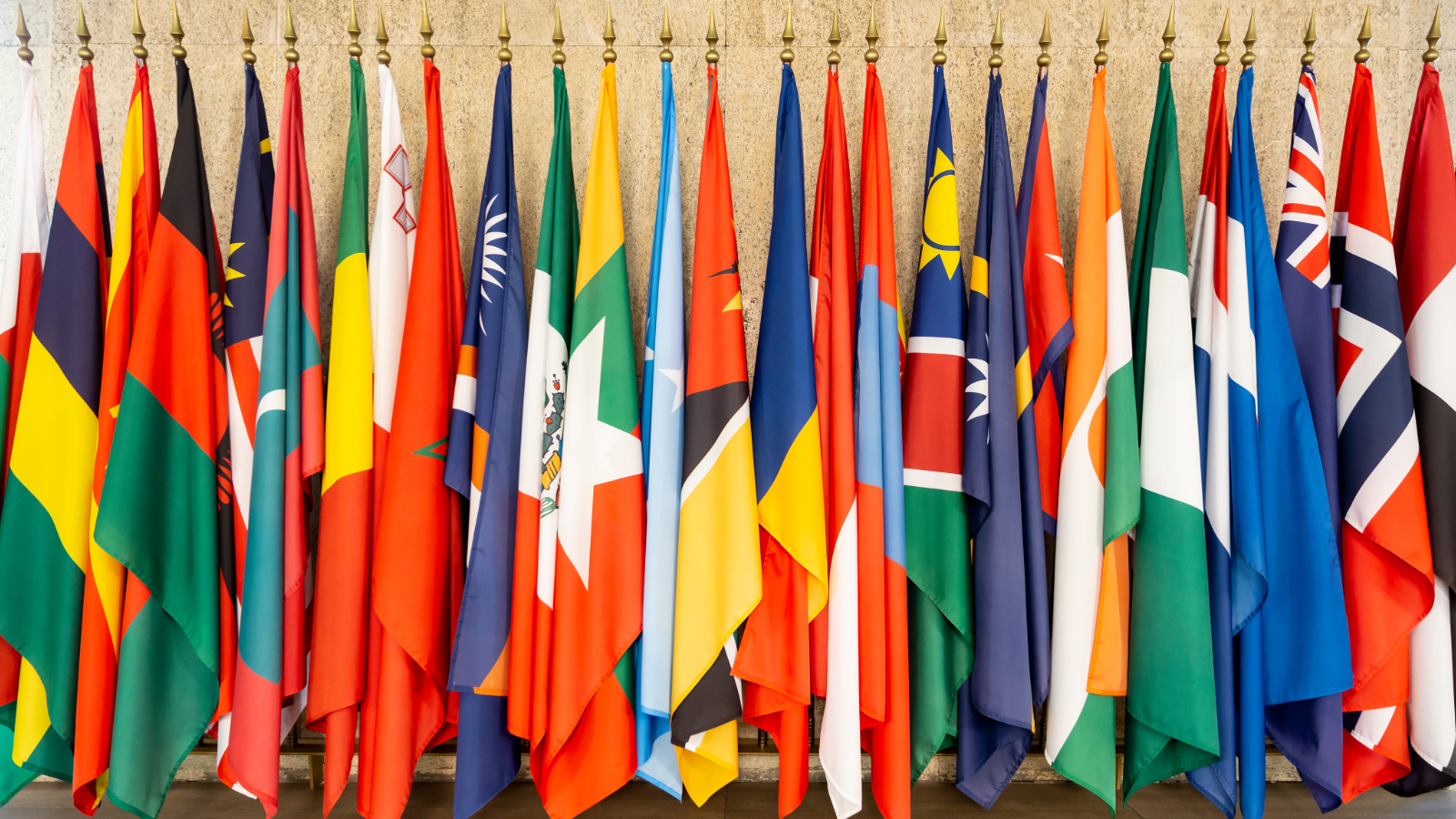 An assortment of United Nations member flags against a tan background