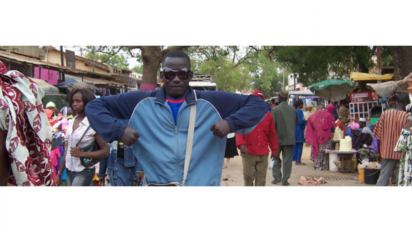 Man in blue shirt in the middle of an African market.