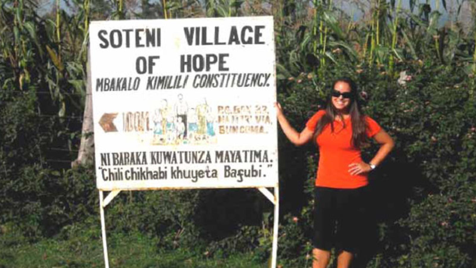 Alexa Gudelsky next to the sign for Soteni Village, Kenya.