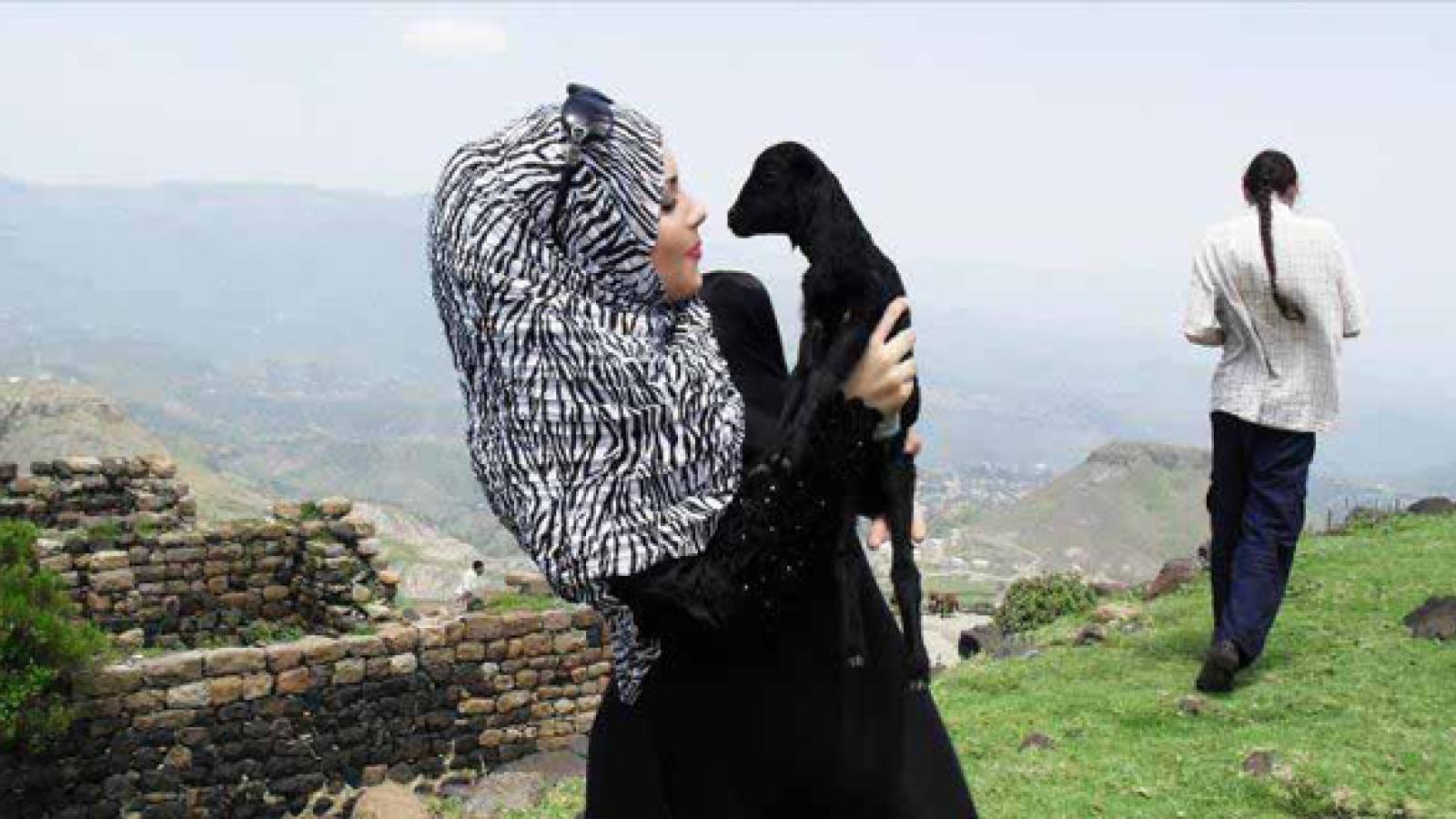 Imaan Ali with a baby lamb on a mountain side in Yemen.